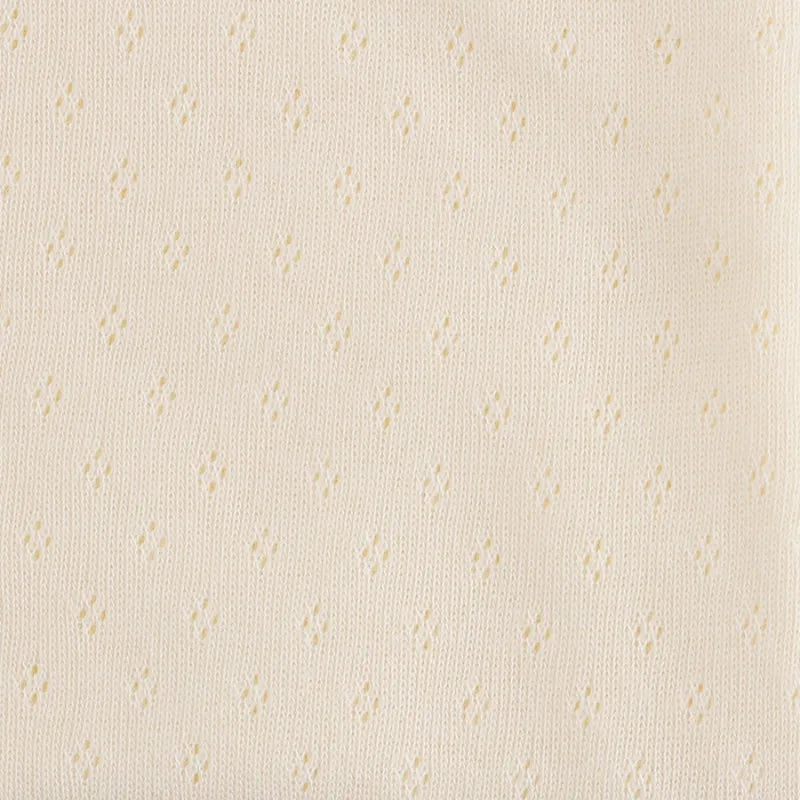 Gros plan sur le Tissu jersey pointelle 100% coton beige clair de Longan Craft France : un tissu jacquard doux avec un petit motif en losange, parfait au mètre pour bricoler de gentils bodys pour bébé ou de délicats sous-vêtements.