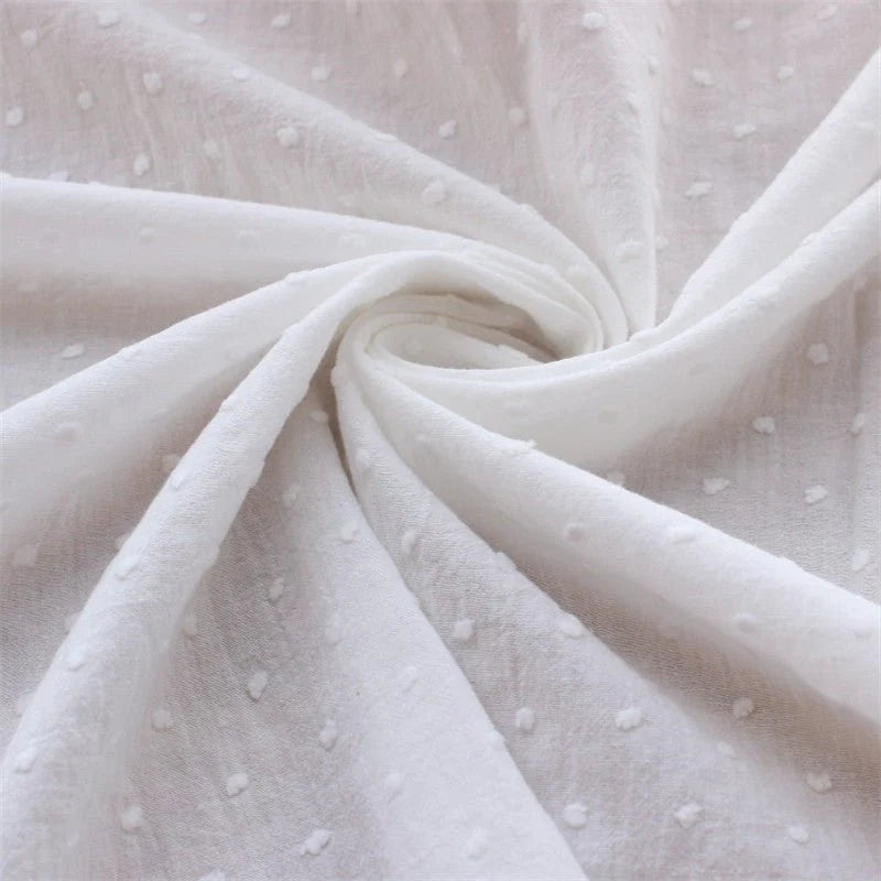 Gros plan sur le Tissu plumetis 100% coton blanc pur au mètre par Longan Craft France, montrant son motif à pois texturé, léger et légèrement transparent-idéal pour vêtements d'été et décoration.
