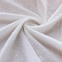Gros plan sur le Tissu plumetis 100% coton blanc pur au mètre par Longan Craft France, montrant son motif à pois texturé, léger et légèrement transparent-idéal pour vêtements d'été et décoration.