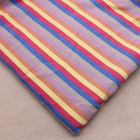 Un tissu French Terry extensible à rayures arc-en-ciel de Longan Craft France, aux tons jaune, rouge, bleu, violet et beige, est posé à plat sur une surface neutre.