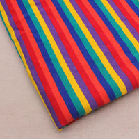 Un morceau de Longan Craft France Tissu French Terry extensible à rayures arc-en-ciel, un tricot de coton doux aux rayures verticales colorées, est présenté sur une surface beige clair.