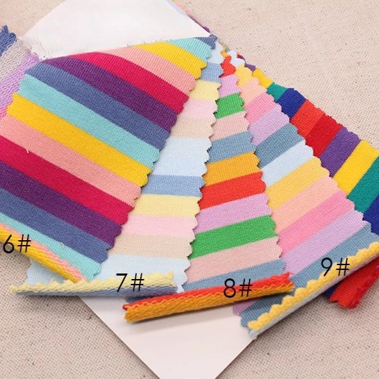 Un présentoir de Tissu French Terry extensible à rayures arc-en-ciel de Longan Craft France, en coton doux pour vêtements de sport, avec des échantillons zigzag numérotés 6#, 7#, 8#, et 9# sur une surface beige.