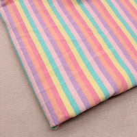 Un morceau de Longan Craft France Tissu French Terry extensible à rayures arc-en-ciel au mètre, présentant des rayures verticales pastel dans les tons rose, jaune, vert, violet et orange, repose sur une surface beige.