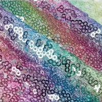 Gros plan sur le Tissu sequin arc-en-ciel au mètre de Longan Craft France, qui présente des paillettes irisées et brillantes de couleur bleue, verte, rose et violette pour un motif éblouissant et coloré, parfait pour les tenues de soirée étincelantes.