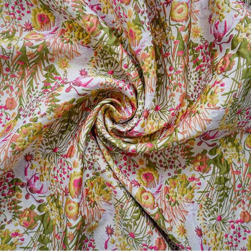 Gros plan sur le tissu brocart rétro floral au mètre de Longan Craft France, un jacquard brodé d'ameublement avec un motif botanique coloré en rose, jaune et vert, rassemblé en spirale pour inspirer un décor rétro pour les chaises et les rideaux.