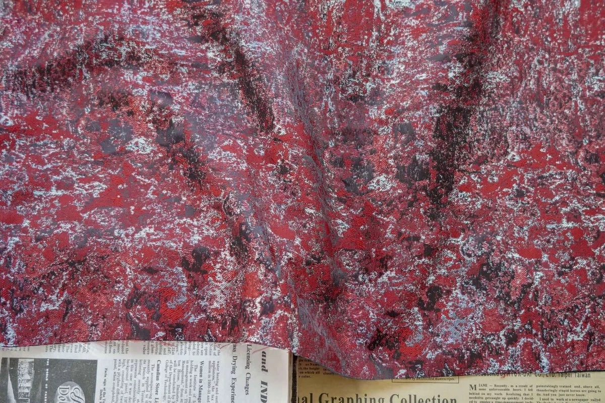 Un morceau de Tissu brocart vert rétro au mètre de Longan Craft France est drapé sur un journal partiellement visible avec du texte et des petites annonces au bas de l'image.