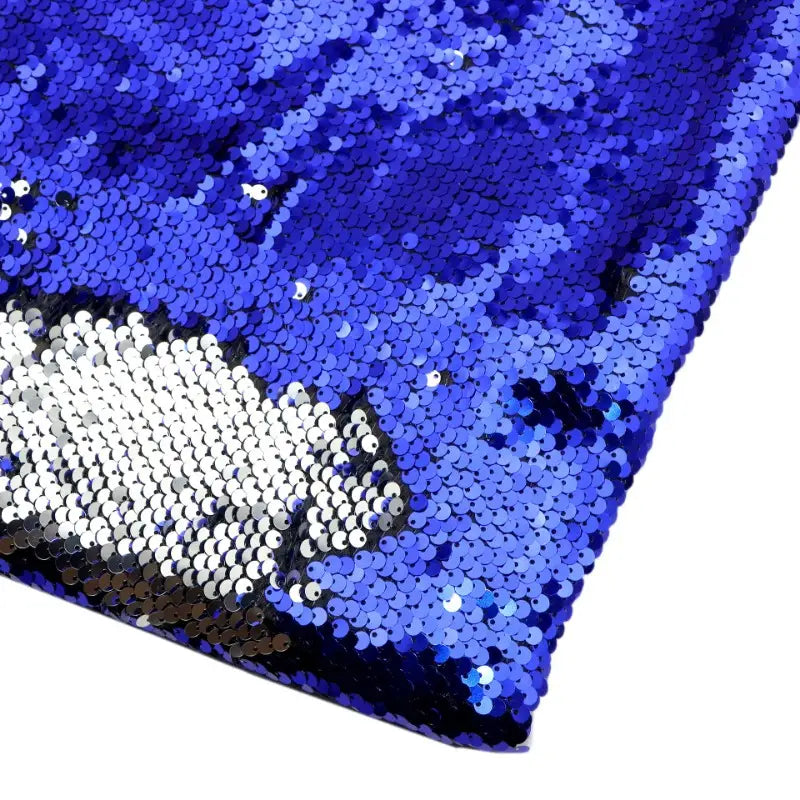 Gros plan sur le Tissu pailleté bicolore réversible au mètre de Longan Craft France, qui présente des paillettes bleues et blanches brillantes qui changent de couleur lorsqu'on les effleure, parfaites pour des accessoires étincelants.