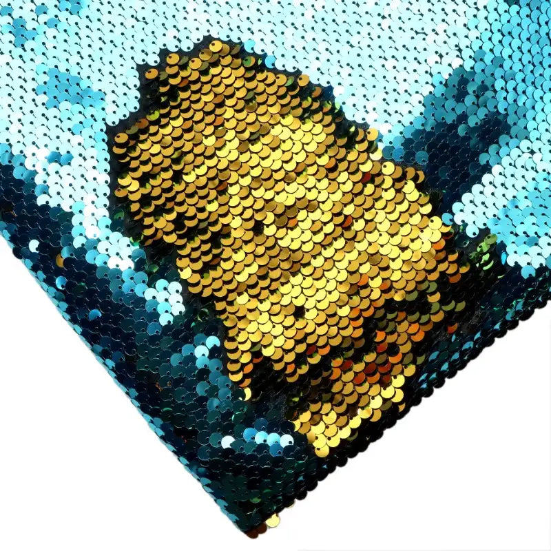 Gros plan sur un visage en paillettes d'or sur fond bleu et blanc, réalisé avec le Tissu pailleté bicolore réversible au mètre de Longan Craft France, un tissu à paillettes réversibles chatoyant, vu de biais.