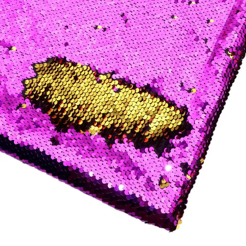 Un gros plan de Tissu pailleté bicolore réversible au mètre de Longan Craft France montre des paillettes roses densément emballées qui, lorsqu'elles sont brossées, révèlent l'or en dessous, créant ainsi une texture ludique et accrocheuse, parfaite pour les accessoires.