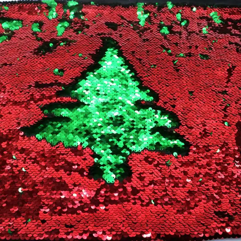 Le Tissu pailleté bicolore réversible au mètre de Longan Craft France représente un sapin de Noël vert sur fond de paillettes rouges, avec des taches vertes éparses, parfait comme matériau scintillant pour les accessoires.