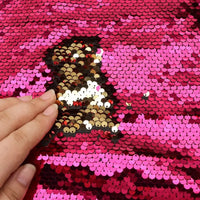 Passez votre main sur le Tissu pailleté bicolore réversible de Longan Craft France pour révéler des paillettes dorées et noires scintillantes sous un rose vif - les couleurs changent à chaque touche pour des accessoires éblouissants.