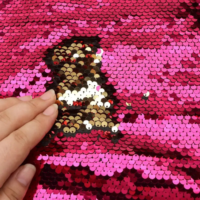 Passez votre main sur le Tissu pailleté bicolore réversible de Longan Craft France pour révéler des paillettes dorées et noires scintillantes sous un rose vif - les couleurs changent à chaque touche pour des accessoires éblouissants.