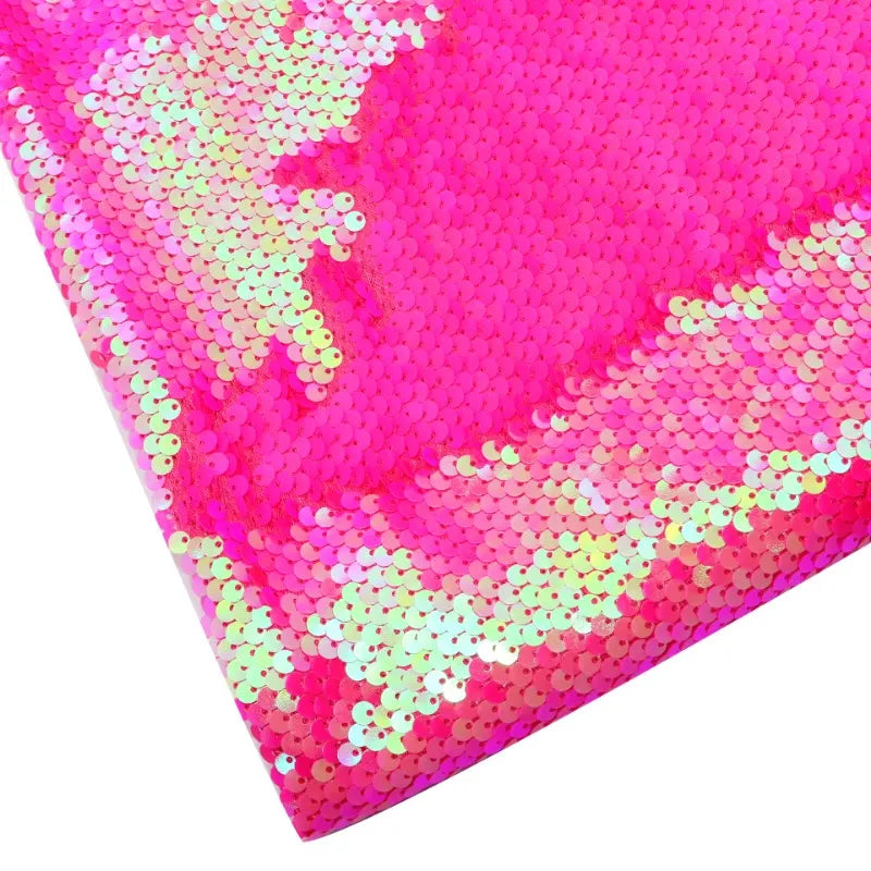 Gros plan sur le tissu pailleté bicolore réversible au mètre de Longan Craft France, montrant des paillettes rose vif et blanc irisé avec un effet de brillance sous un certain angle.