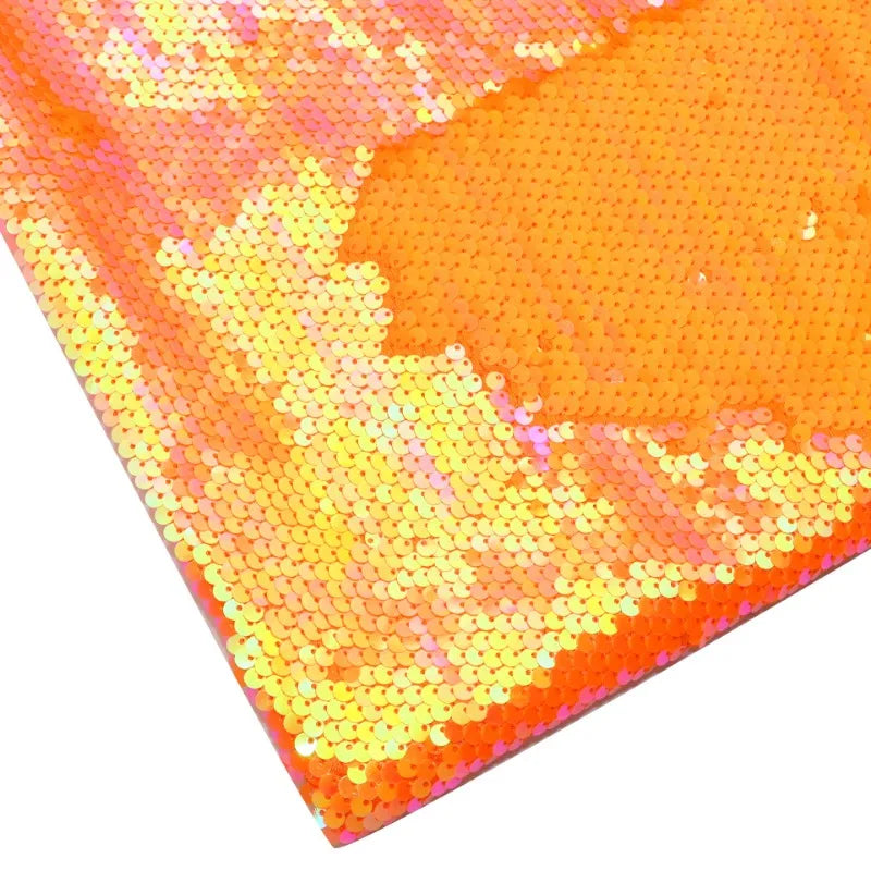 Gros plan sur le tissu pailleté bicolore réversible au mètre de Longan Craft France, qui présente de petites paillettes orange brillantes au fini irisé. La vue à plat met en valeur la texture chatoyante unique de cette matière scintillante idéale pour accessoires.
