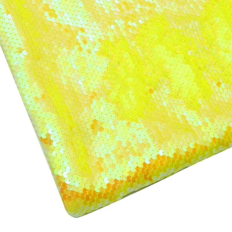 Gros plan sur le tissu pailleté bicolore réversible au mètre de Longan Craft France, qui présente des paillettes jaunes uniformes. Seuls le coin et le côté sont montrés, mettant en valeur cette matière scintillante idéale pour accessoires.