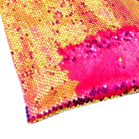 Un gros plan du tissu pailleté bicolore réversible au mètre de Longan Craft France montre des paillettes principalement dorées, dont une partie est brossée pour révéler un rose vif en dessous, sur un fond blanc.