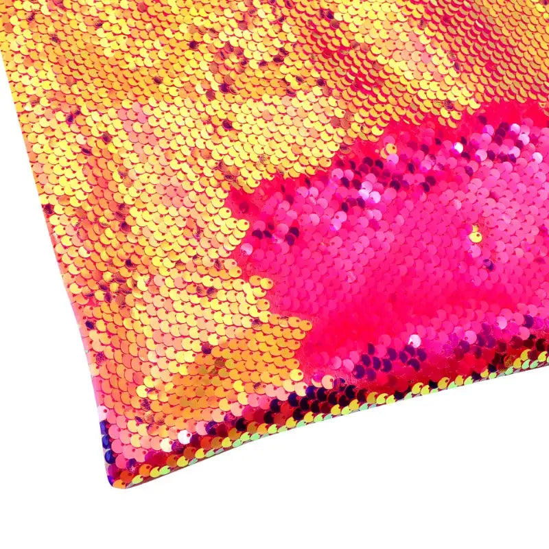 Un gros plan du tissu pailleté bicolore réversible au mètre de Longan Craft France montre des paillettes principalement dorées, dont une partie est brossée pour révéler un rose vif en dessous, sur un fond blanc.