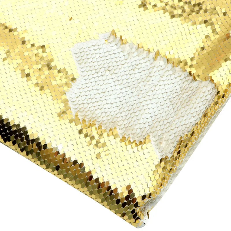 Un gros plan du tissu pailleté bicolore réversible au mètre de Longan Craft France montre un contraste accrocheur entre l'or et le blanc, créé en retournant les paillettes de cette matière scintillante pour accessoires.
