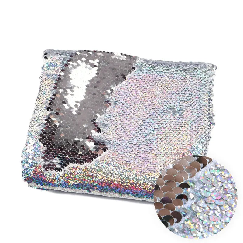 Une pièce de Longan Craft France Tissu pailleté bicolore réversible au mètre montre des paillettes argentées et arc-en-ciel brossées pour révéler des couleurs différentes, avec un insert en gros plan mettant en évidence les effets réversibles étincelants.