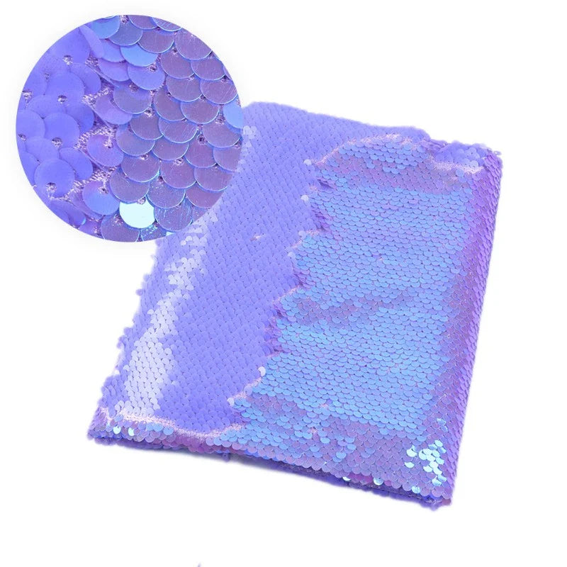 Une pièce rectangulaire de Longan Craft France Tissu pailleté bicolore réversible au mètre est présentée, montrant en gros plan les petites paillettes superposées qui recouvrent ce tissu chatoyant pour accessoires.
