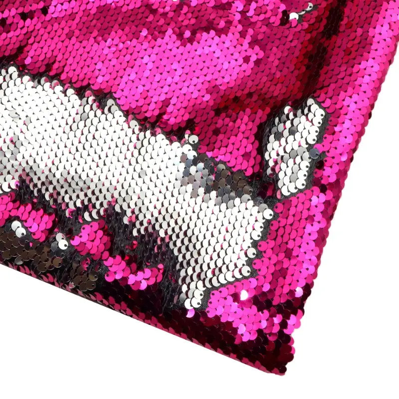 Un gros plan du Tissu pailleté bicolore réversible au mètre de Longan Craft France montre des paillettes magenta et argentées brossées dans des directions différentes, créant un effet bicolore saisissant sur ce tissu étincelant.
