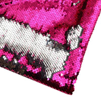 Un gros plan du Tissu pailleté bicolore réversible au mètre de Longan Craft France montre des paillettes magenta et argentées brossées dans des directions différentes, créant un effet bicolore saisissant sur ce tissu étincelant.