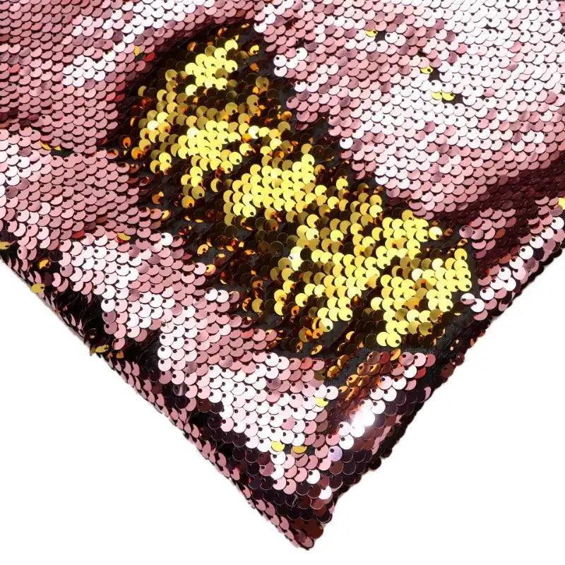 Gros plan sur le Tissu pailleté bicolore réversible au mètre de Longan Craft France, montrant des paillettes roses dont la partie dorée est révélée pour un effet éblouissant. Cette matière scintillante est parfaite pour les accessoires.