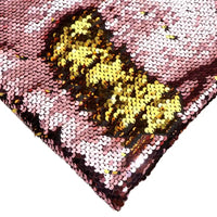 Gros plan sur le Tissu pailleté bicolore réversible au mètre de Longan Craft France, montrant des paillettes roses dont la partie dorée est révélée pour un effet éblouissant. Cette matière scintillante est parfaite pour les accessoires.