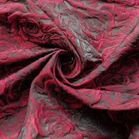 Tissu brocart jacquard rose au mètre de Longan Craft France, en dégradé rouge et noir avec motif floral en relief, présenté en spirale pour mettre en valeur la texture et les détails du tissu.