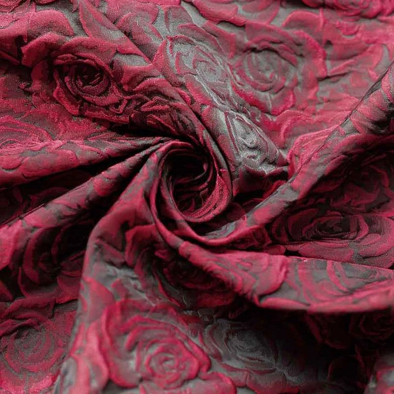 Tissu brocart jacquard rose au mètre de Longan Craft France, en dégradé rouge et noir avec motif floral en relief, présenté en spirale pour mettre en valeur la texture et les détails du tissu.