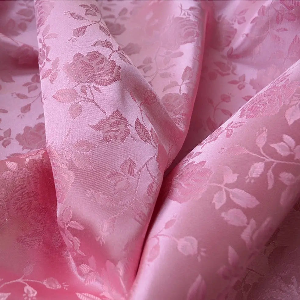 Le Tissu satin jacquard rose au mètre de Longan Craft France est un tissu satiné rose à motifs floraux, au lustre subtil, idéal pour la confection de robes. Sa surface lisse se drape magnifiquement, mettant en valeur d'élégants motifs de roses et de feuilles.
