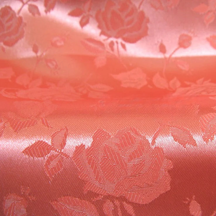 Gros plan sur le Tissu satin jacquard rose au mètre de Longan Craft France - un satin rose clair à la finition brillante et aux motifs floraux complexes, idéal pour la confection de robes élégantes ou pour celles qui recherchent un tissu à motifs floraux raffiné.