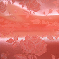Gros plan sur le Tissu satin jacquard rose au mètre de Longan Craft France - un satin rose clair à la finition brillante et aux motifs floraux complexes, idéal pour la confection de robes élégantes ou pour celles qui recherchent un tissu à motifs floraux raffiné.