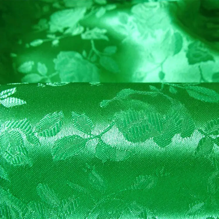 Un gros plan sur le Tissu satin jacquard rose au mètre de Longan Craft France montre sa surface réfléchissante à motifs floraux, idéale comme textile satiné à motifs floraux pour la confection de peignoirs.