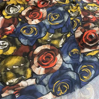 Un gros plan de Tissu en maille piquée imprimé roses au mètre de Longan Craft France montre des fleurs stylisées bleues, rouges, jaunes et blanches avec des feuilles vertes sur un fond translucide - idéal pour les robes manches courtes ou le DIY couture.