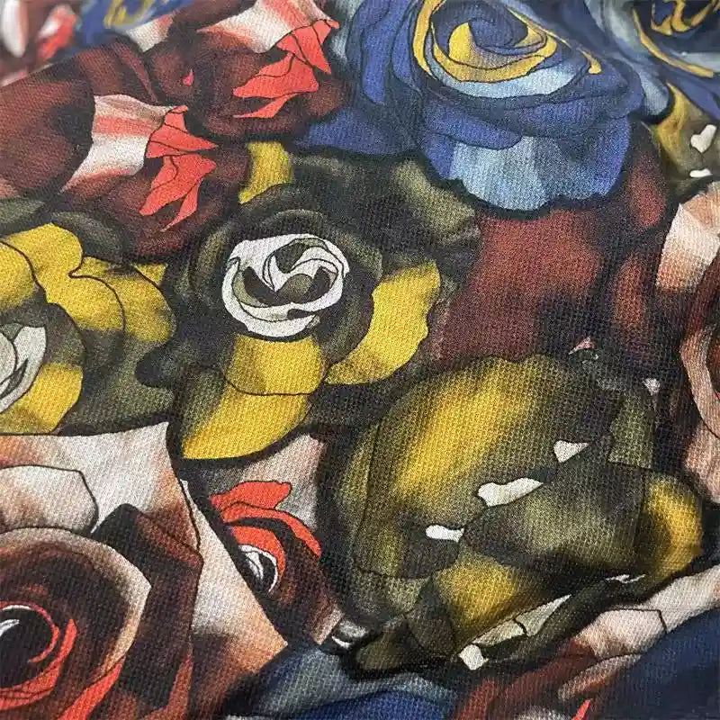 Gros plan sur le tissu en maille piquée imprimé roses au mètre de Longan Craft France, un tissu piqué 100 % coton pour robes à manches courtes, montrant des roses colorées sur fond sombre et une texture respirante idéale pour la couture DIY.