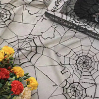 Une toile d'araignée en tulle pailleté de Longan Craft France recouvre la surface. Le livre "The Solace of Soar" est posé sur le dessus, avec un bouquet de fleurs artificielles rouges et jaunes dans le coin.