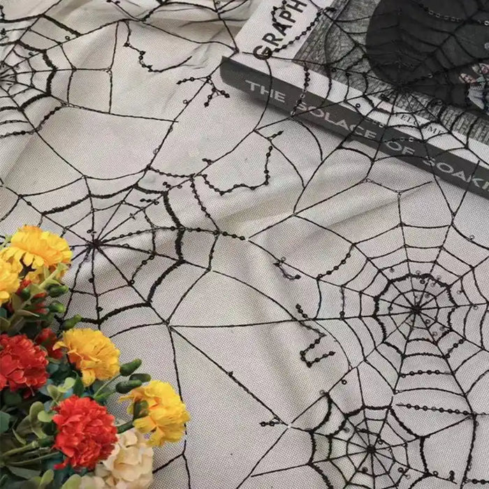Une toile d'araignée en tulle pailleté de Longan Craft France recouvre la surface. Le livre "The Solace of Soar" est posé sur le dessus, avec un bouquet de fleurs artificielles rouges et jaunes dans le coin.