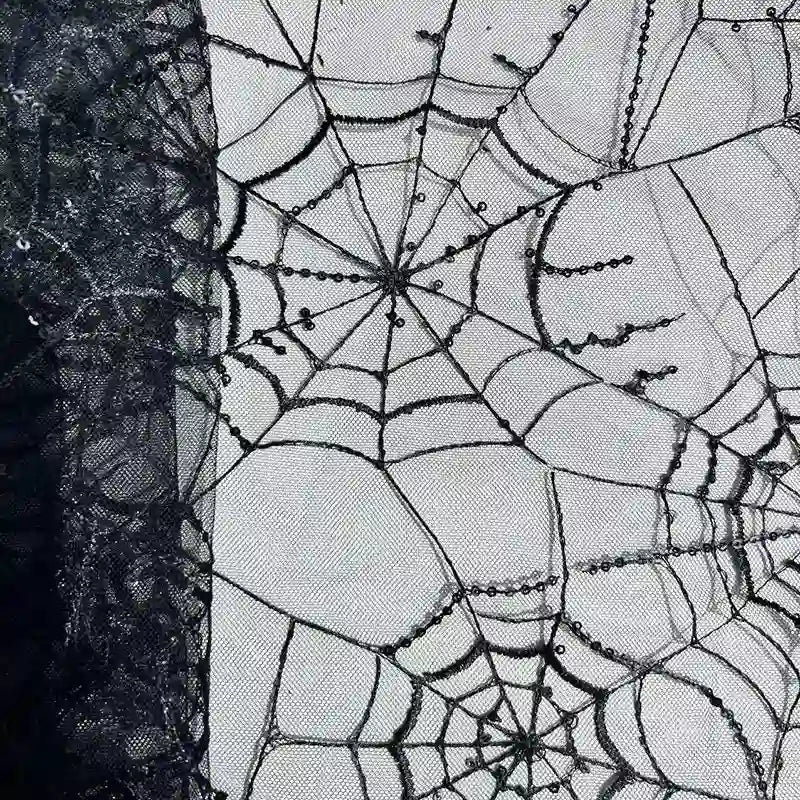 Gros plan sur le tissu en tulle brodé de sequins au mètre de Longan Craft France, qui présente un motif de toile d'araignée avec des broderies complexes - idéal pour les décors d'Halloween et les projets de bricolage effrayants.