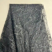 Le Tissu en tulle brodé de sequins au mètre de Longan Craft France présente un motif de toile d'araignée en paillettes argentées sur du tulle noir - idéal pour des décors et des costumes d'Halloween étincelants.