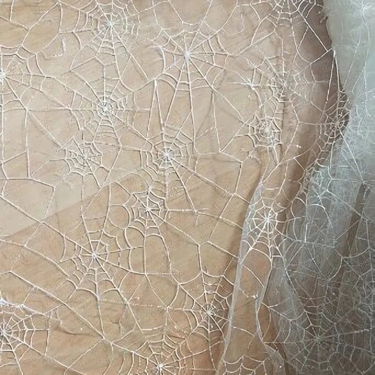 Le Tissu en tulle brodé de sequins au mètre de Longan Craft France, avec son délicat motif de toile d'araignée, crée un effet de superposition et de translucidité, idéal pour les décorations d'Halloween.