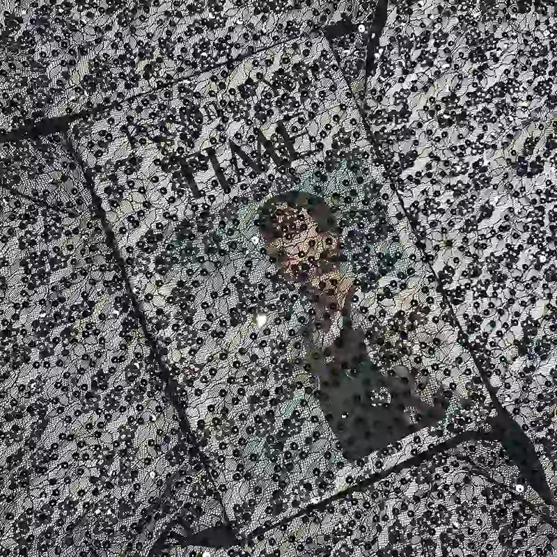 Une couverture de magazine Time, partiellement cachée par des gouttes d'eau sur le verre, prend un effet texturé et flou - rappelant le chatoiement et la complexité du Tissu dentelle à paillettes au mètre de Longan Craft France pour les robes de mariée.