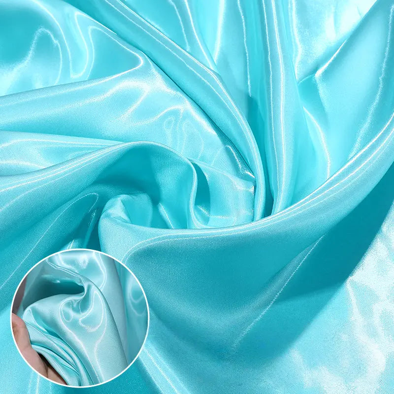 Satin liquide brillant au mètre de Longan Craft France, idéal pour robes de demoiselle d'honneur, drapé et froncé en turquoise. Un zoom montre la texture satinée et réfléchissante du tissu polyester parfait pour tenues de cérémonie.