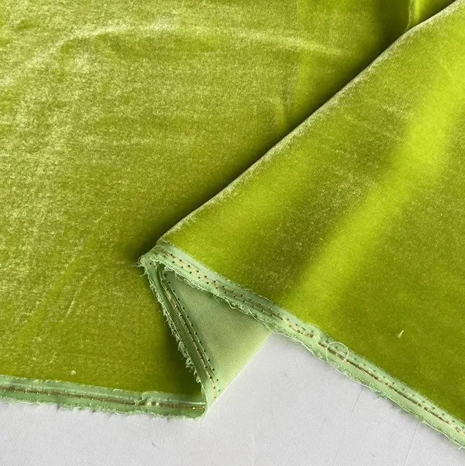 Un gros plan du Tissu velours de soie au mètre de Longan Craft France en vert clair montre sa texture douce de soie de mûrier et son bord cousu, avec le recto et le verso visibles. Parfait pour les peignoirs, la couture, l'artisanat et la tapisserie.