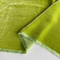 Un gros plan du Tissu velours de soie au mètre de Longan Craft France en vert clair montre sa texture douce de soie de mûrier et son bord cousu, avec le recto et le verso visibles. Parfait pour les peignoirs, la couture, l'artisanat et la tapisserie.