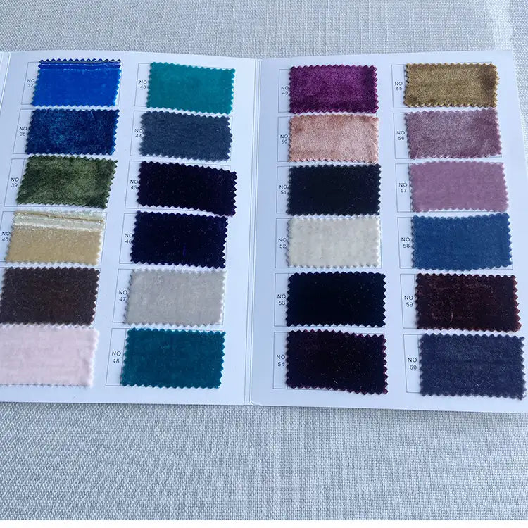 Un livret ouvert de Longan Craft France présente des échantillons de Tissu velours de soie au mètre - du velours de soie de mûrier doux pour les robes, la couture, l'artisanat et l'ameublement - chacun numéroté sur des pages blanches, reposant sur une surface légèrement texturée.