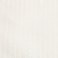Gros plan sur le Tissu jersey pointelle coton simple face de Longan Craft France, un tissu en tricot de coton côtelé de couleur crème ou blanc cassé avec de petits détails texturés en forme de losange, idéal pour confectionner des bodys et des pyjamas pour bébés.