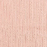 Gros plan sur le Tissu jersey pointelle coton simple face au mètre de Longan Craft France : tissu rose pâle, doux et lisse avec de petits oeillets verticaux - idéal pour le body DIY ou le pyjama bébé et les projets délicats.