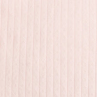 Gros plan sur la pointelle en jersey de coton rose pâle de Longan Craft France, qui présente des rayures verticales côtelées et des œillets en losange régulièrement espacés. Elle est idéale pour les bodys ou les pyjamas de bébé. Disponible au mètre.