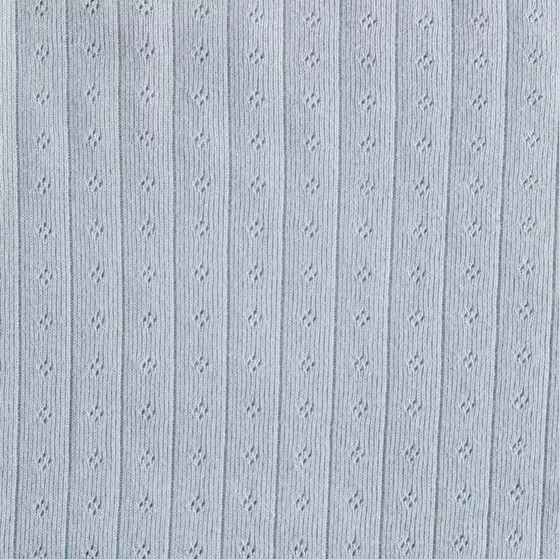 Gros plan sur le tissu Longan Craft France Tissu jersey pointelle coton simple face au mètre, un uni tricoté doux avec de délicates nervures verticales et des trous en losange - un tissu de bricolage idéal pour les bodys de bébé ou les pyjamas douillets.
